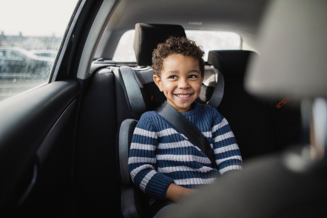young-boy-smiling-while-sitting-in-car-seat-during-road-trip