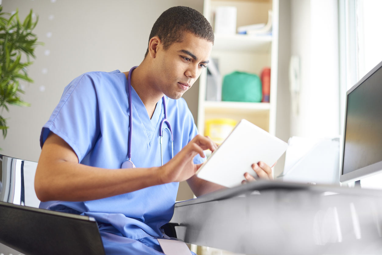male healthcare worker hunched over his desk working