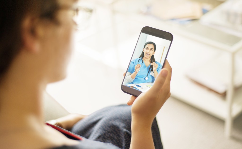 person-holding-smartphone-during-telehealth-appointment-with-doctor-on-video