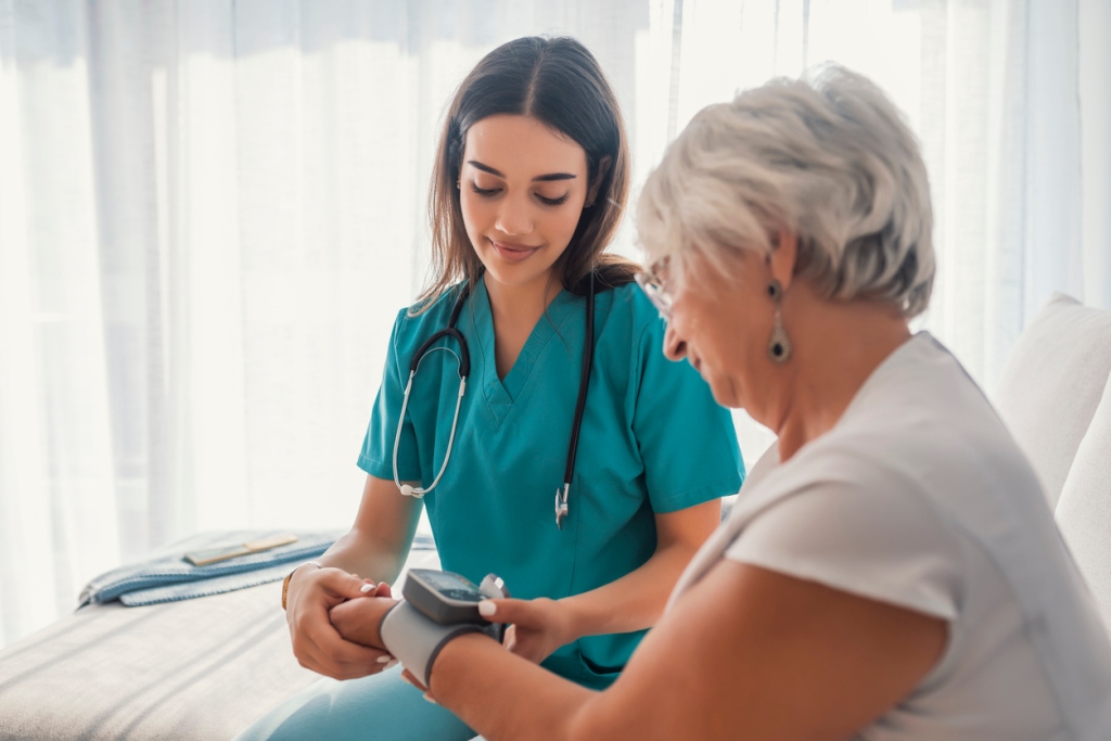 female registered nurse taking blood pressure with wrist cuff of senior woman